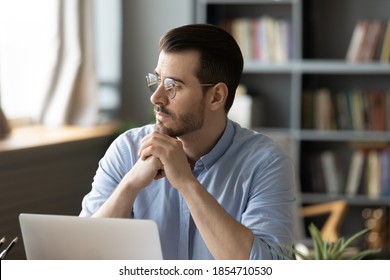 Pensive businessman in glasses distracted from computer work looking in distance thinking about project, pondering solve current issues lost in thoughts planning. Business solutions and vision concept