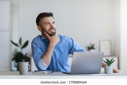 Pensive businessman sitting at workplace in modern office, thinking about new business idea, touching chin and looking aside with smile, free space - Powered by Shutterstock