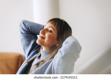 Pensive businesswoman relaxing in an office lobby with her hands at the back of her head. Young businesswoman contemplating new ideas while taking a break in a modern office. - Shutterstock ID 2179195511