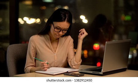 Pensive businesswoman thinking of plan writing notebook, sitting front of laptop - Shutterstock ID 1382912450