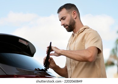 Pensive Car Service Worker Replace Windshield Wipers On Car Standing Outdoors