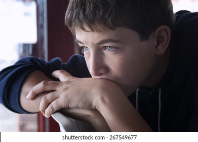 Pensive child looking through a window - Powered by Shutterstock