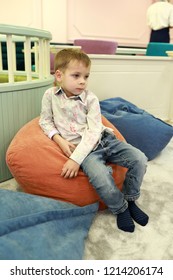 Pensive Child Sitting On Bean Bag Chair