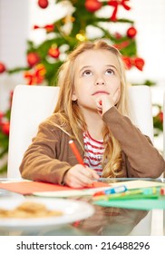 Pensive Child Writing Wishlist To Santa Claus For Christmas