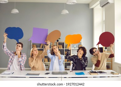 Pensive College Students Looking Up At Multicolored Speech Bubbles Sitting At Desk In Class. Puzzled Young People At Loss Thinking Hard Together Trying To Remember Answer To School Test Paper Question