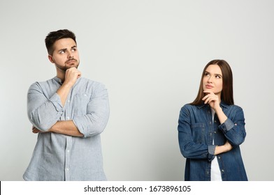 Pensive couple on light background. Thinking about answer for question