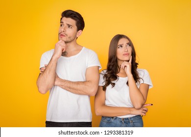 Pensive couple thinking and looking away on yellow studio background