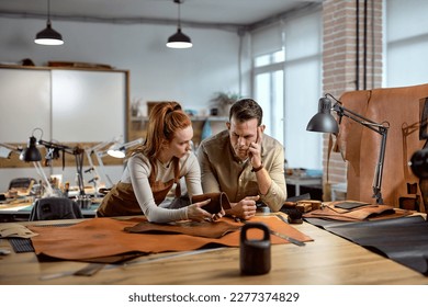 pensive craftsmen try to find out the type of leather, standing at the table, close up portrait, girl holds Leathers with Different Textured Surfaces to her partner - Powered by Shutterstock