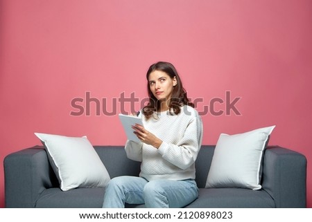 Pensive creative young business woman mother writing notes, ideas, make to do list, planning shopping, sitting on sofa