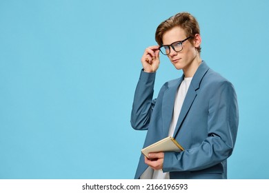 Pensive Cute Guy In A Jacket And Glasses On A Blue Background