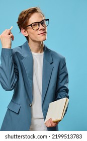 Pensive Cute Guy In A Jacket And Glasses On A Blue Background