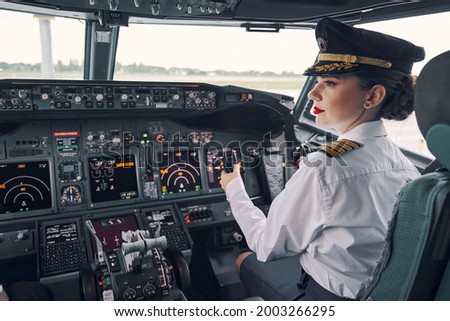 Pensive dark-haired woman co-pilot seated in the cockpit