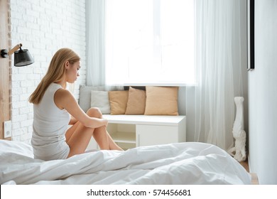 Pensive Depressed Young Woman Sitting And Thinking On Bed In The Morning