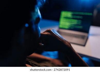 Pensive developer writing code late at night, working on programming software, debugging system issues, ensuring cyber security protection during dark room session, close-up back view.
