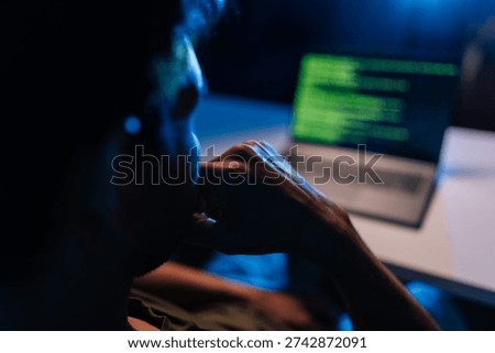 Pensive developer writing code late at night, working on programming software, debugging system issues, ensuring cyber security protection during dark room session, close-up back view.