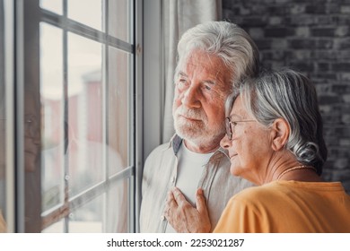 Pensive elderly mature senior man in eyeglasses looking in distance out of window, thinking of personal problems. Old woman wife consoling and hugging sad husband, copy space - Shutterstock ID 2253021287