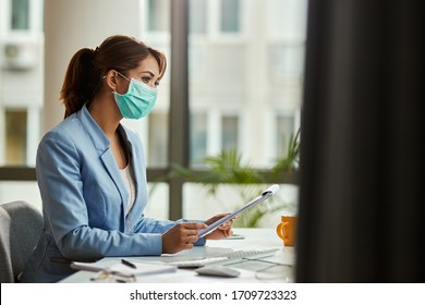 Pensive Female Entrepreneur With Face Mask Working On Business Reports In The Office. Copy Space.