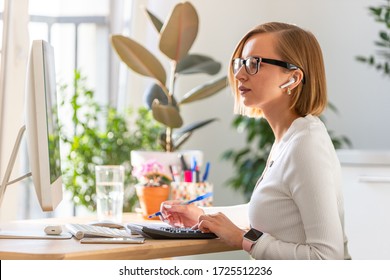 Pensive Freelancer Woman In Glasses Work On Computer, Using Calculator To Calculate The Invoice, Planning Expenses From Home Office During Self-isolation. Cozy Workplace. Online Business. 