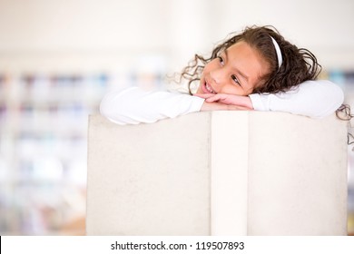 Pensive girl at the library with a big book - Powered by Shutterstock