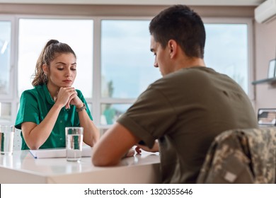 Pensive Healthcare Worker Thinking While Having A Meeting With Depressed Military Officer Suffering From Post-traumatic Syndrome.  