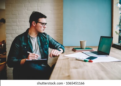 Pensive hipster guy in eyewear watching training webinar on laptop computer spending time on e learning, male designer working on freelance browsing information for project on netbook drawing sketch - Shutterstock ID 1065451166