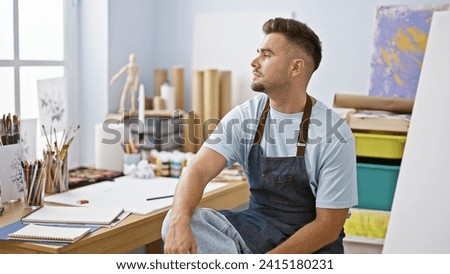 Pensive hispanic man in studio with art supplies contemplating his next creation.