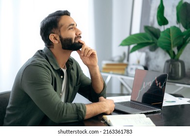 Pensive Indian or Arabian crypto investor, stock exchange broker, cryptocurrency expert, sit in a modern office, thoughtfully looks ahead, plans a strategy to achieve high profits in the crypto market