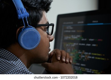 Pensive Indian software developer looking at programming code