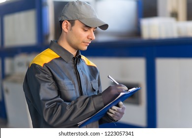 Pensive industrial worker writing on a document