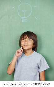 Pensive japanese boy with lightbulb drawn on chalkboard in school - Shutterstock ID 183147257