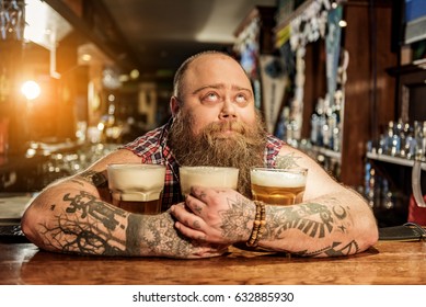 Pensive Male Embracing Mugs Of Alcohol Beverage