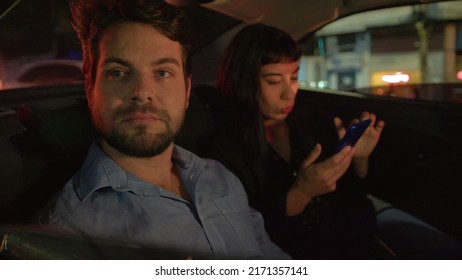 Pensive man in car backseat stuck in traffic at night after with with female partner looking at smartphone device waiting for vehicle to move - Powered by Shutterstock