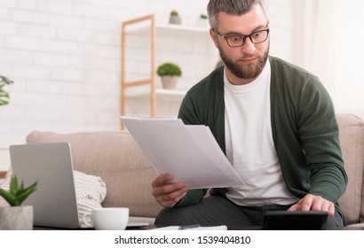 Pensive Man Checking On Incomes At Home, Using Calculator, Copy Space