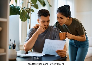 Pensive man and his wife going through bills while planning their home finances at home. - Powered by Shutterstock