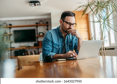 Pensive man looking at laptop while sitting at wooden table, portrait. - Shutterstock ID 1643327950