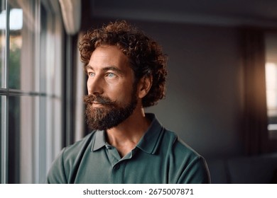 Pensive man looking through the window at home. Copy space. 