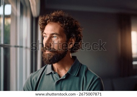 Pensive man looking through the window at home. Copy space. 