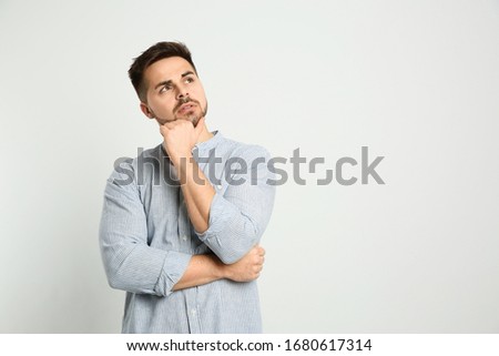 Pensive man on light background, space for text. Thinking about answer to question