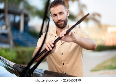 Pensive Man Replace Windshield Wipers On Car Standing Outdoors. Car Service Concept