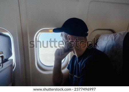 A pensive man sits at the window on an airplane