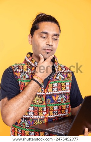 Pensive man thinking how to solve business tasks on laptop, isolated over studio background. Employee caught in brainstorming process, doing marketing analysis on notebook