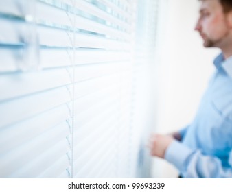 Pensive man thinking of something behind venetian blind - Powered by Shutterstock