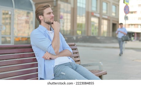 Pensive Man Thinking While Sitting Outdoor On Bench