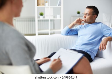 Pensive Man Trying To Relax On Sofa During Psychological Therapy Session