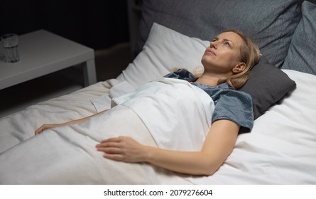 Pensive Mature Woman In Pajamas Lying Awake In Bed With White Linen And Looking At Ceiling. Sleepless And Thoughtful Female Person At Night.