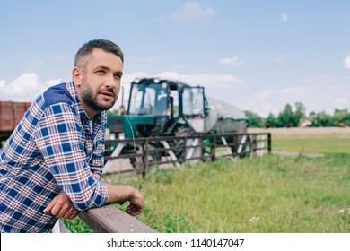 Pensive Middle Aged Farmer Leaning At Railing And Looking Away At Farm 