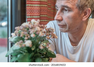 Pensive Middle-aged Man Sits In Restaurant And Looks Thoughtfully Out Window While Waiting For Couple On Date