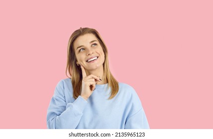 Pensive millennia Caucasian girl isolated on pink studio background think or plan. Thoughtful smiling young woman make decision pondering of good deal or offer. Choice and dilemma concept.