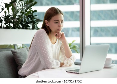 Pensive millennial Caucasian female employee sit at desk working on laptop thinking planning, thoughtful young woman work or study on computer, make notes, take online course or training - Shutterstock ID 1673171752