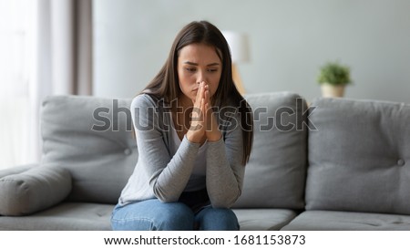 Pensive millennial girl sit on sofa in living room look in distance thinking or pondering of problem, thoughtful young woman lost in thoughts feel frustrated or distressed at home, drama concept